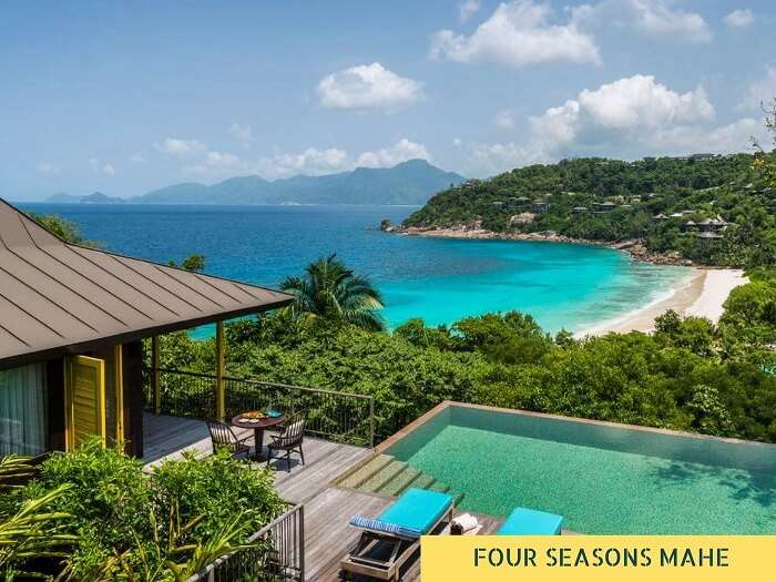 The swimming pool of Four Seasons resort on Mahe Island with the sea and the hills in the background