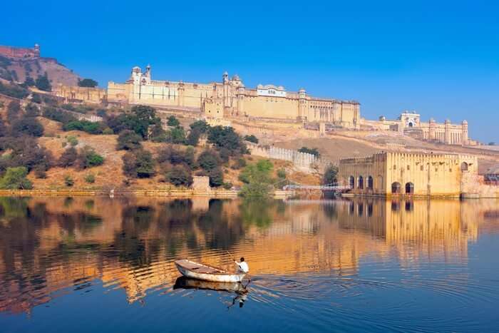 An oarsman rows a boat in the Maota lake in front of Amber fort