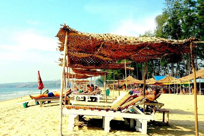 Tourists relax at the recliners and boat shacks at Querim Beach