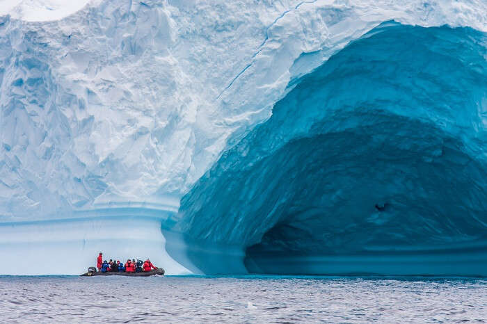 Zodiac in front of enormous ice berg in Antarctica