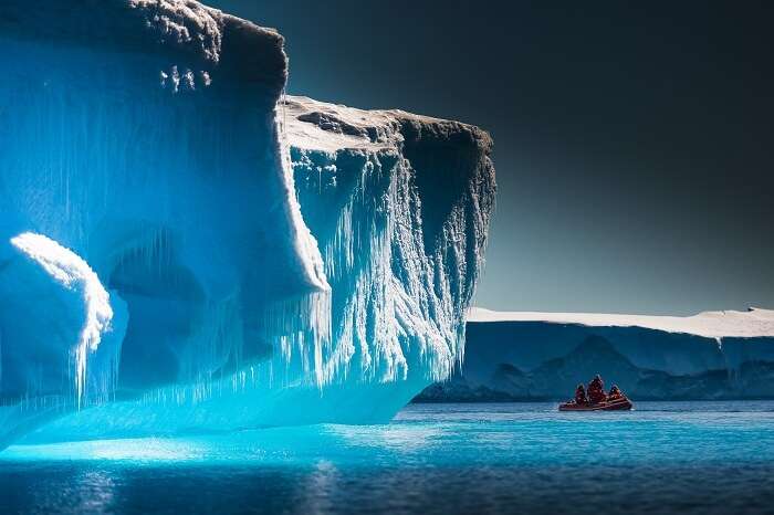 Scientists exploring the icebergs of Antarctica by a boat