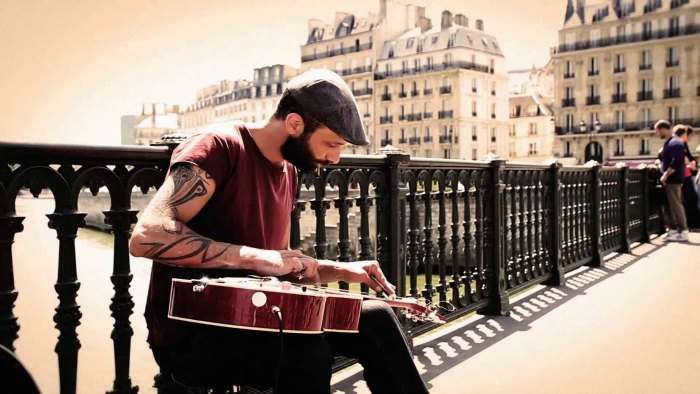 An indie club strumming on his guitar