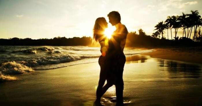 A honeymoon couple enjoying a romantic moment during sunset at a beach in Kerala