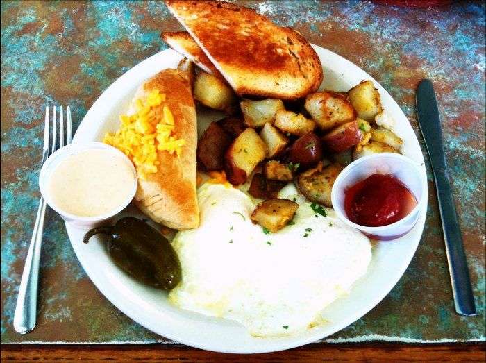 Brazilian plate full of meat, corn beef, tousled egg whites, and bread toasts with cheese.