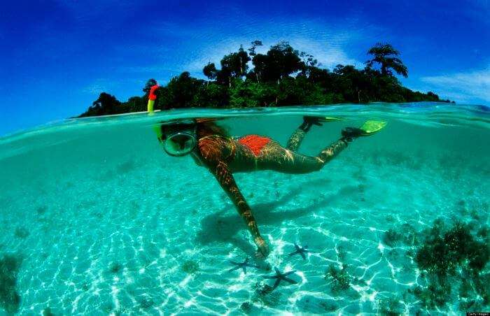 A young girl admiring the rich sea life while snorkeling at Pereybere beach