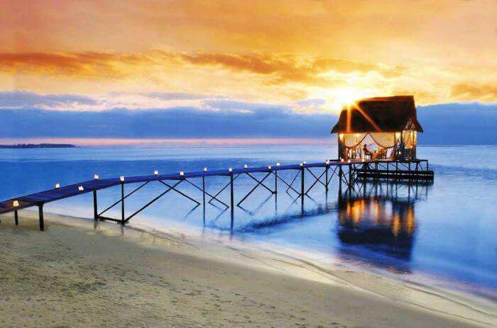 A candle lit pathway leading to an overwater shack, set for a romantic evening at Trou Aux Biches in Mauritius