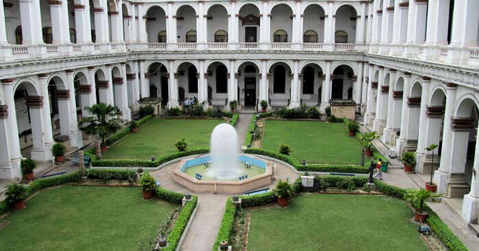 a fountain in the middle of a garden surrounded by a building
