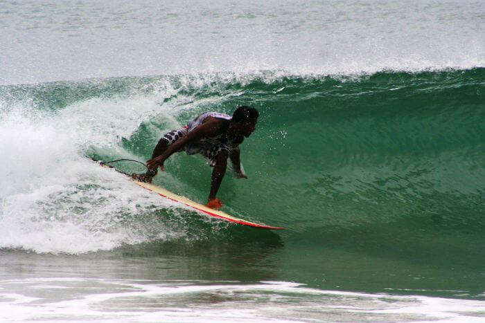 A young man surfs on the waves at the Covelong Beach
