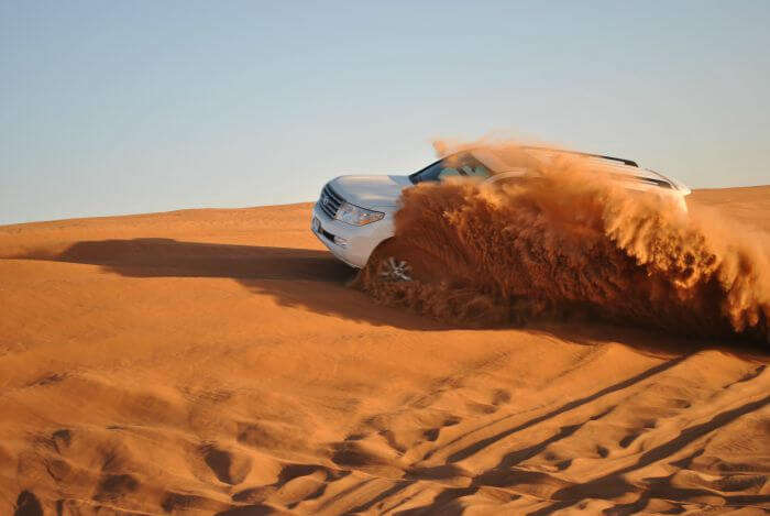 A SUV amidst red brown desert sand in Dubai