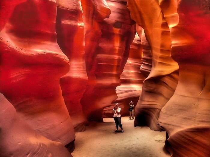 Tourists click photographs while walking through the reddish yellow Antelope Canyon