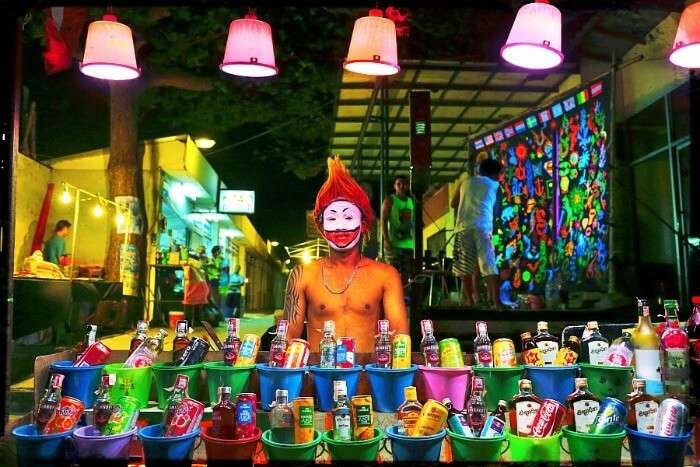 Person with face painting selling buckets in Full Moon Party in Thailand