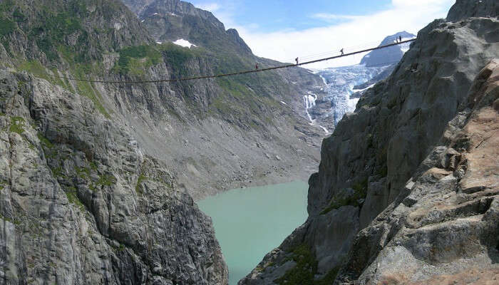 Tourists crossing the scary Trift Bridge in Switzerland