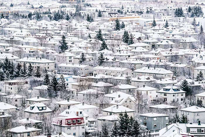 Snow gleams over the houses in Reykjavik and the midnight sun shines above them