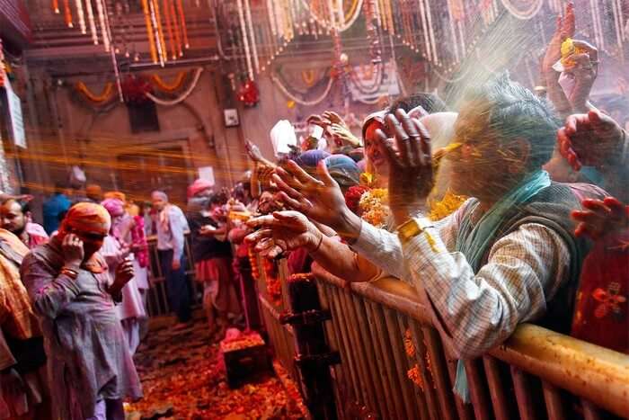 Priest's shower colorful Holi water on revelers during Holi in Mathura