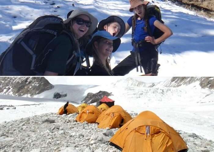 Girls pose for a picture while others set up tents on the Auli Gorson winter trek