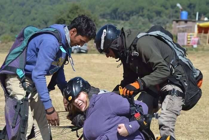 A female tourist getting her parachute removed at the landing site after paragliding in Bir Billing