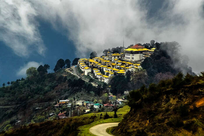 Clouds pass over the yellow roofed monastery at Tawang on an early summer morning