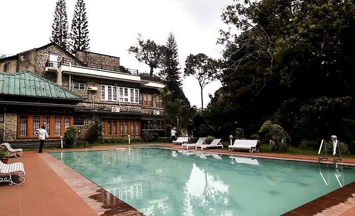 The pool-side area overlooking the victorian facade of Aranya Nivas Resort in Thekkady