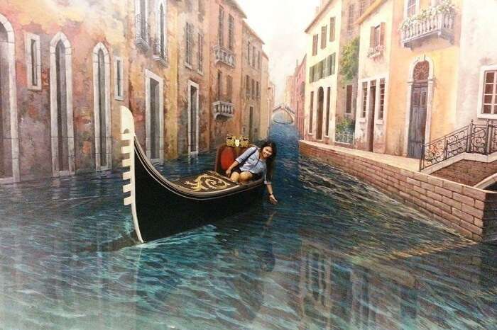 A tourist blends in the 3D painting at the Art In Paradise