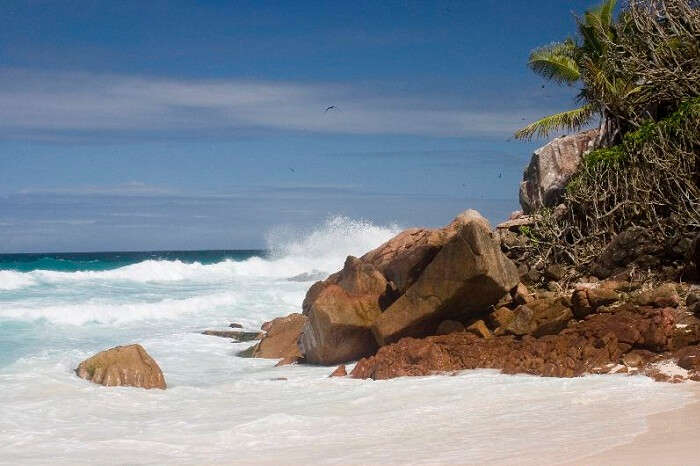 The waves slashing against the large boulders at a beach on Aride Island