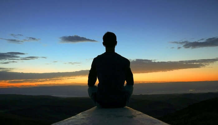 silhouette of a man sitting in a meditative pose