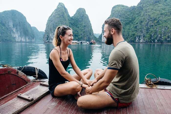 Couple holding hands and smiling on the deck of cruise ship at Ha long Bay