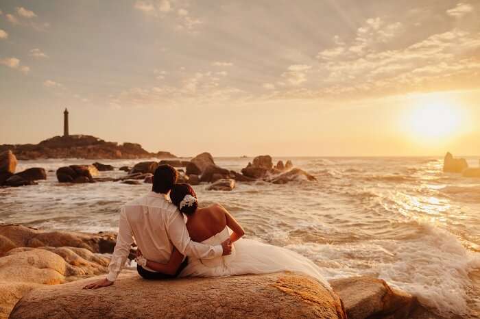 Couple enjoys a sunset view opposite to the lighthouse in Vietnam