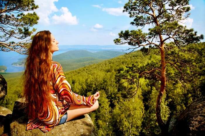 A beautiful woman sitting the lush green mountains in India