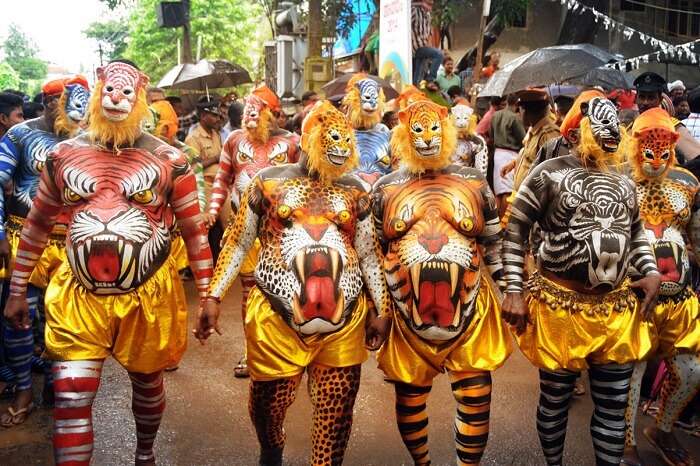 Participants of the parade walk with tiger masks and painted bodies during the Athachamayam Festival