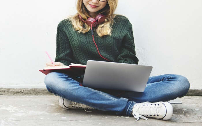 A woman working with a laptop and taking notes