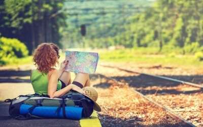 A female traveler reading a map beside rail tracks