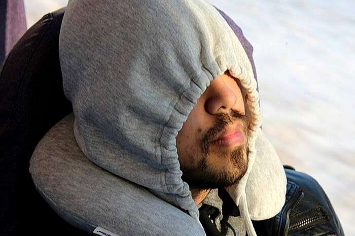A traveler wearing a hoodie pillow