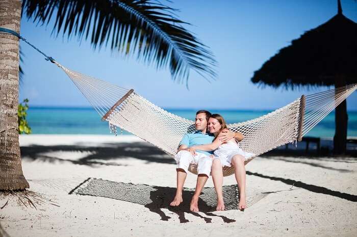 Young romantic couple relaxing in hammock on tropical beach of Zanzibar island