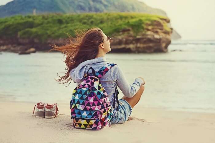 a girl sitting on a beach, free and independent