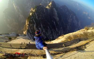 A person with selfie stick doing cliff walking in Huashan Mountain - one of the most extreme adventure activities