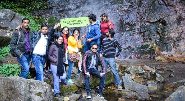 the whole group posing before the waterfall