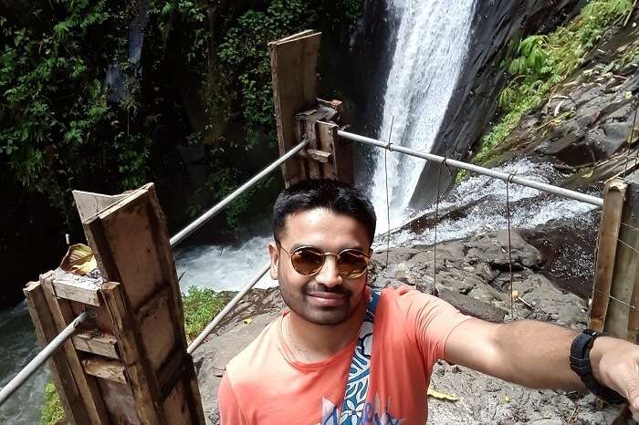 A man taking a selfie near a waterfall