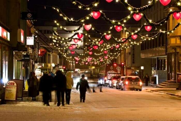 People in Tromso walk past a decorated street during Christmas