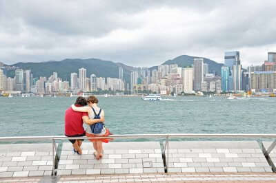 A honeymoon couple in Hong Kong sits at a waterfront