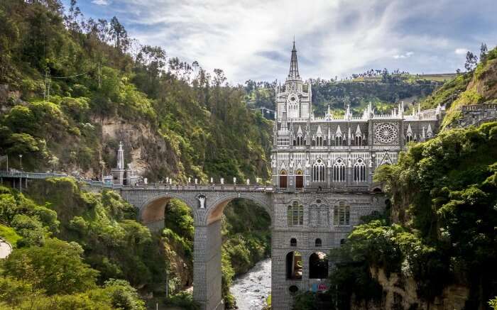 Shot of Las Lajas Sanctuary with hills, river and bridge