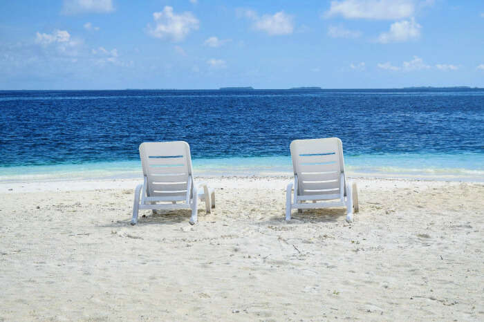 easy chairs on pearly white sands and turquoise waters beyond in maldives