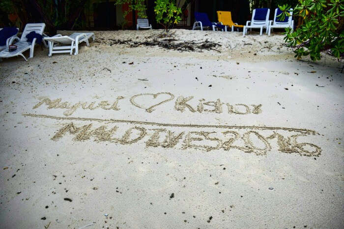 kishor & wife writing their names in the white sands of maldives