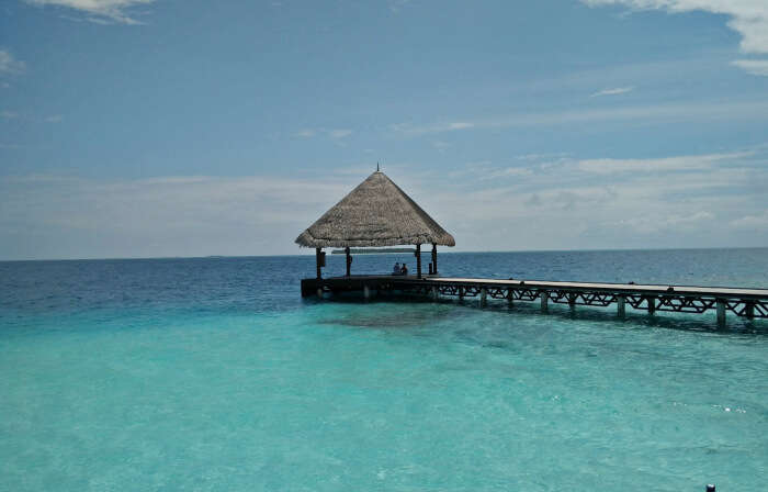 thatched huts in maldives resort and serene blue waters beyond