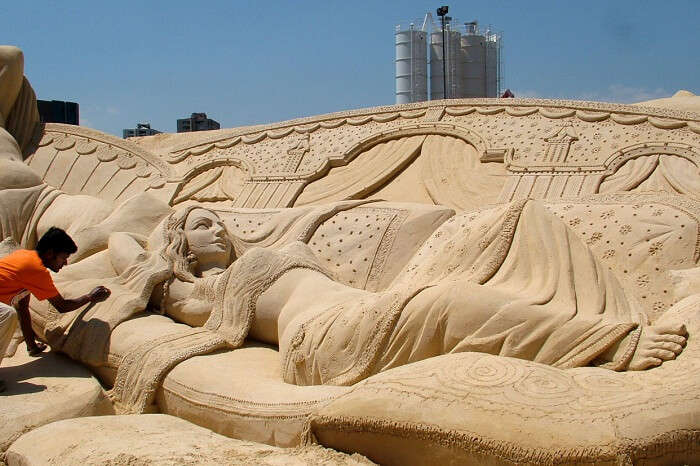 A sand artist making a beautiful piece of sand art at the Golden Beach of Puri