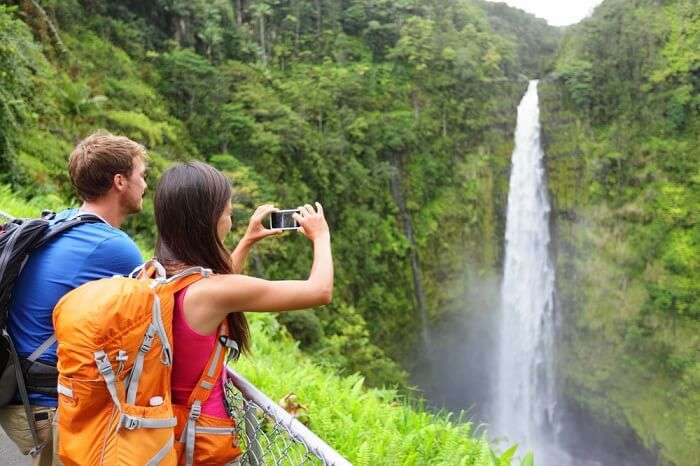 A couple taking pictures of Akaka Falls waterfall on the Big Island on their honeymoon in Hawaii