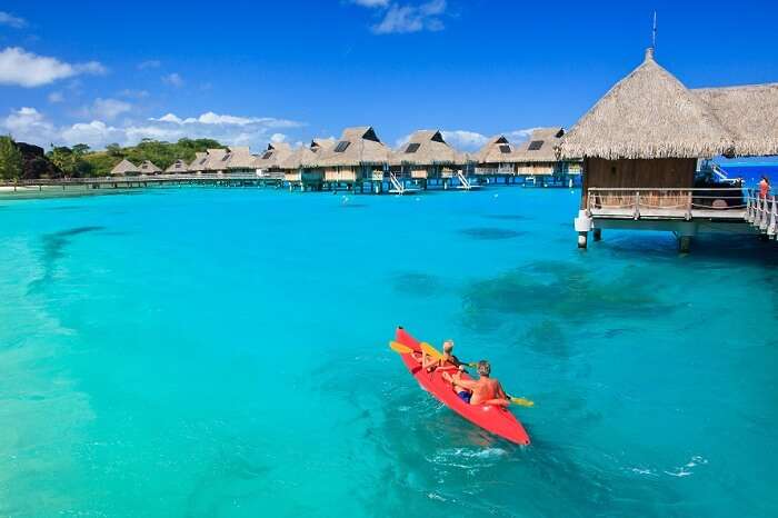 A couple kayaking near the overwater villas in Bora Bora