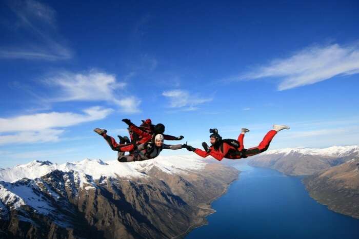 Two professional skydivers accompany an adventurer while skydiving in New Zealand