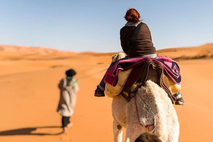 Woman traveling on camel led by a berber nomad