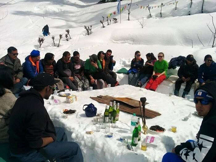 A group of campers having a meal outside the igloo in Manali