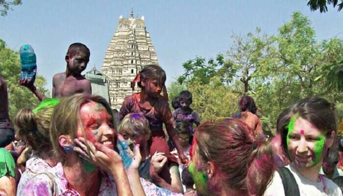 Foreign tourists enjoying applying colors at each other during holi celebrations at Hampi